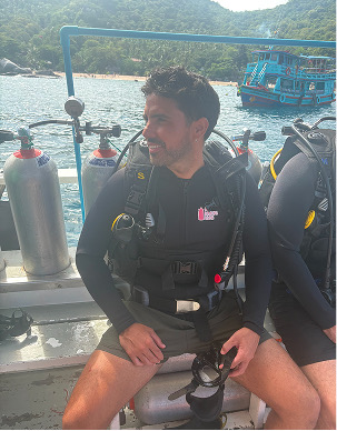 Adrián con traje de neopreno y equipo de buceo en un barco